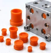 Orange masking plugs beside a machined block